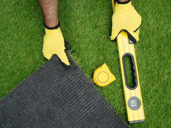 Man's hands with the artificial grass roll and tools